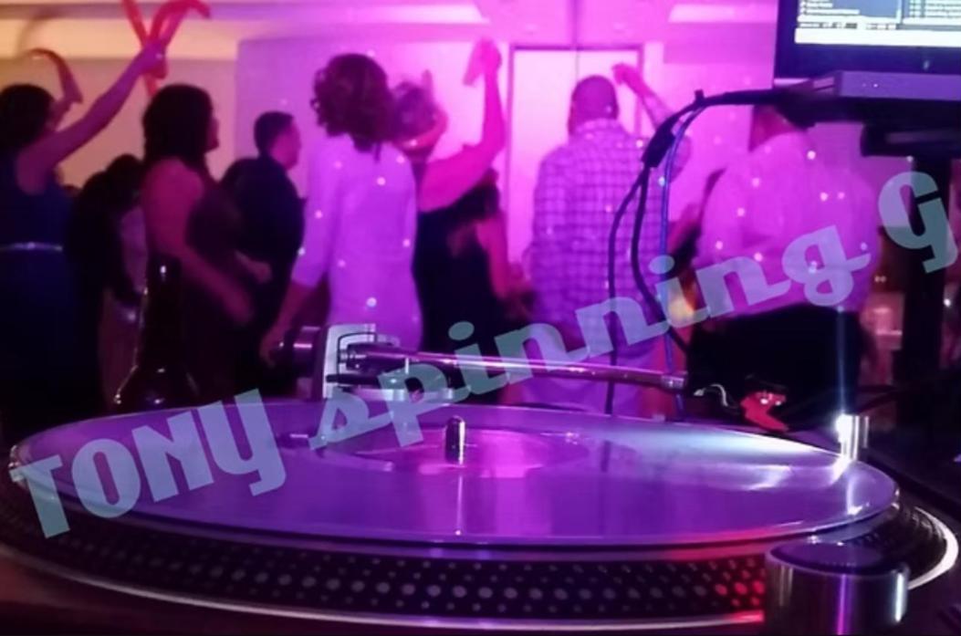 Guests dancing under pink lights behind a turntable